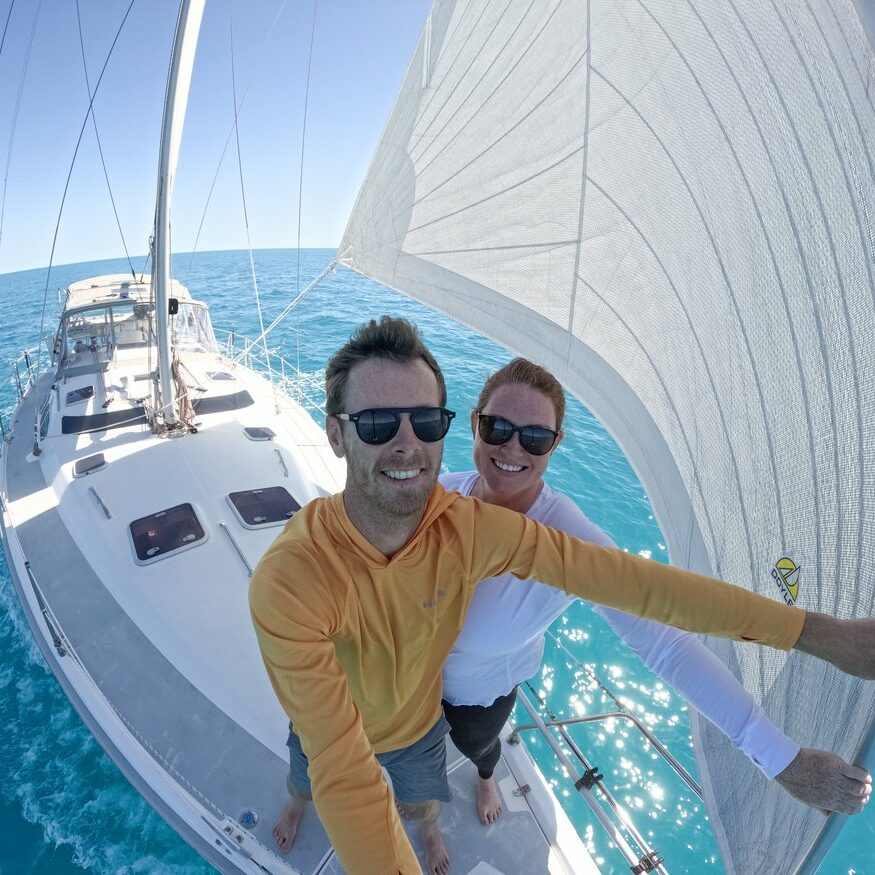 Jeff and Claire standing on a sailboat in the Bahamas
